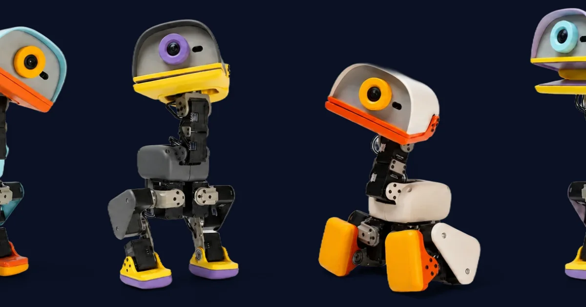 Four Microduck robots from Pollen Robotics in different colourways, each a 25 centimetre bipedal robot with a large single camera eye set in a rounded head, a coloured beak, visible servo motors in the legs, and moulded feet.